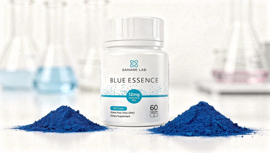 Sanare Lab “Blue Essence” supplement bottle on a white lab surface with two piles of blue powder and blurred laboratory glassware in the background.